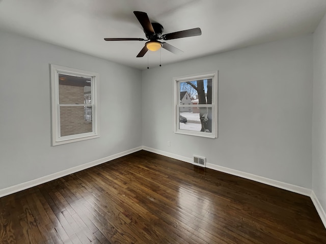 spare room with a ceiling fan, visible vents, baseboards, and dark wood-style flooring