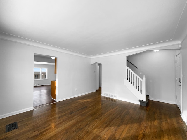 unfurnished living room featuring baseboards, visible vents, hardwood / wood-style floors, and stairs