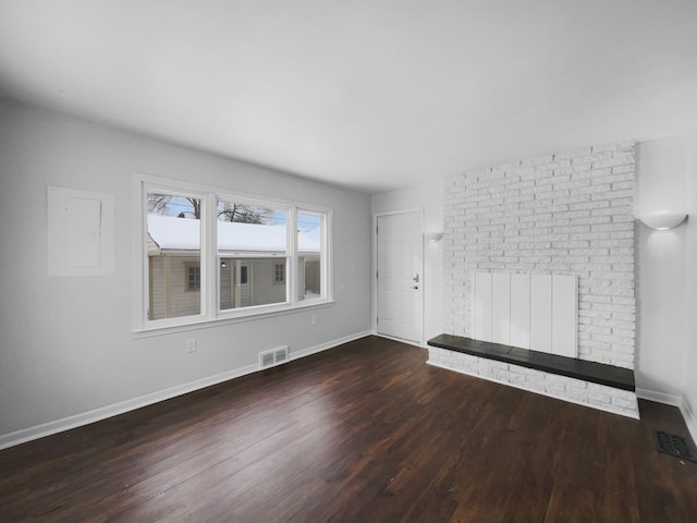 unfurnished living room with visible vents, a fireplace, baseboards, and wood finished floors