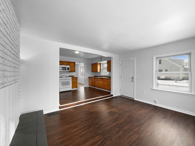 unfurnished living room with dark wood-style floors, baseboards, and visible vents