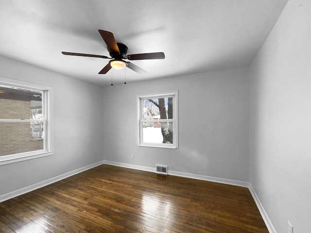 empty room with dark wood-style floors, visible vents, baseboards, and a ceiling fan