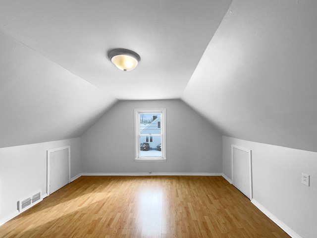 additional living space featuring lofted ceiling, wood finished floors, visible vents, and baseboards