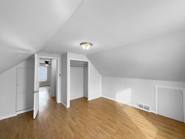 bonus room featuring baseboards, visible vents, vaulted ceiling, and light wood finished floors