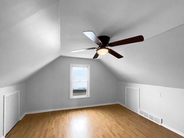 additional living space featuring lofted ceiling, light wood-type flooring, visible vents, and baseboards