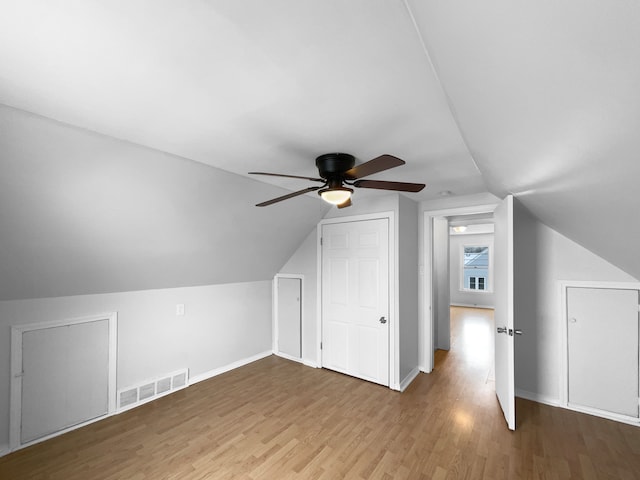 additional living space with visible vents, a ceiling fan, vaulted ceiling, wood finished floors, and baseboards