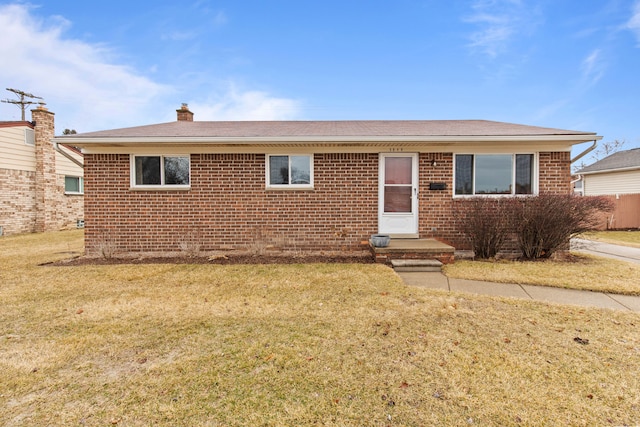 single story home featuring brick siding, a front lawn, and a chimney