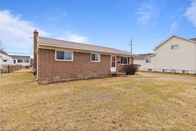 view of front of property featuring a front yard, entry steps, a chimney, and brick siding