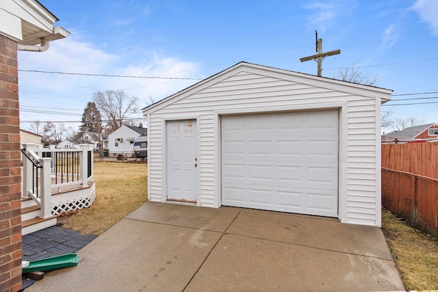 detached garage with concrete driveway and fence