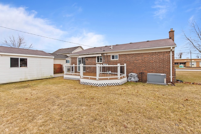 rear view of property with brick siding, a lawn, a chimney, and fence