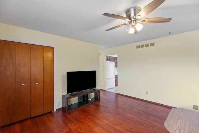 living area with visible vents, ceiling fan, baseboards, and wood finished floors