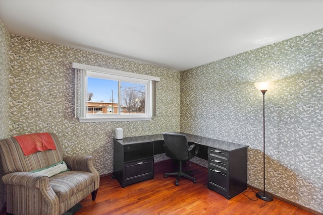 office area with wallpapered walls and wood finished floors