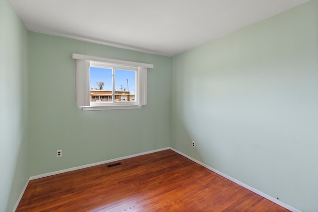 spare room with baseboards, visible vents, and dark wood-type flooring