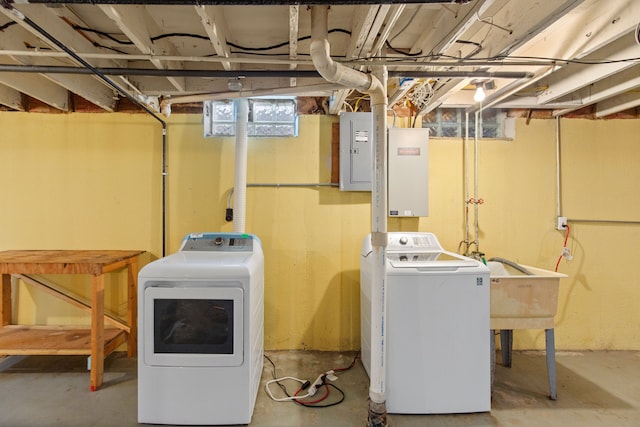 clothes washing area featuring laundry area, washer and clothes dryer, a sink, and electric panel