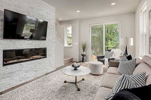 living room with baseboards, a stone fireplace, wood finished floors, and recessed lighting