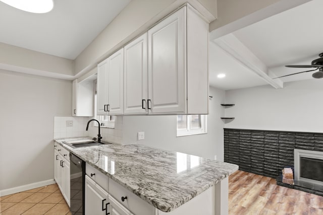 kitchen featuring a sink, baseboards, white cabinets, decorative backsplash, and dishwasher