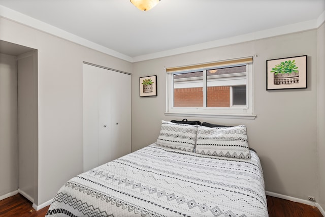 bedroom with dark wood-style floors, baseboards, and a closet