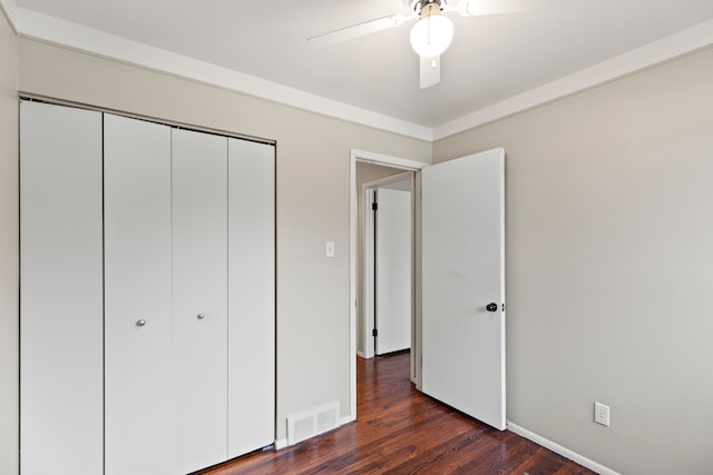 unfurnished bedroom featuring a closet, visible vents, dark wood finished floors, and ceiling fan