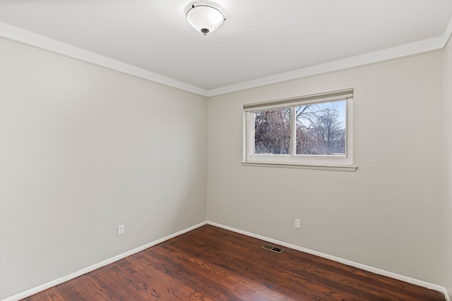 spare room with baseboards, visible vents, and dark wood-style flooring