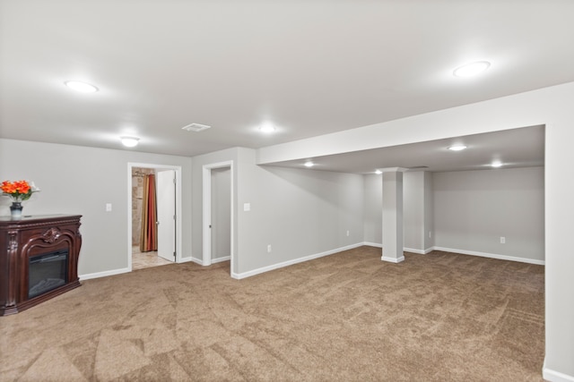 finished below grade area with carpet, baseboards, and a glass covered fireplace