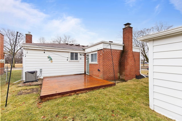 back of property featuring a chimney, a lawn, central AC unit, fence, and a wooden deck