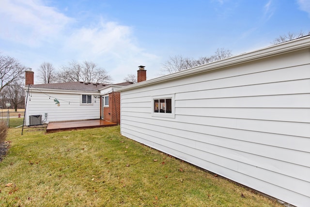 back of house featuring a lawn, a chimney, fence, a wooden deck, and central air condition unit