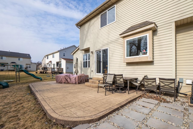 rear view of house with entry steps, a patio, and a playground