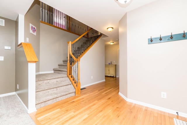 stairway with visible vents, baseboards, and wood finished floors