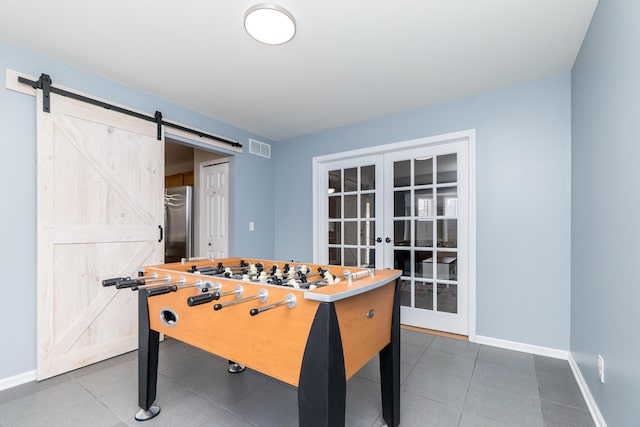 rec room with a barn door, visible vents, baseboards, tile patterned flooring, and french doors