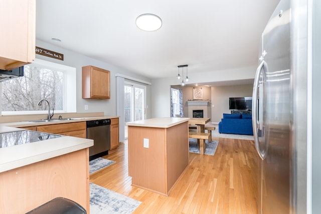 kitchen featuring a kitchen island, appliances with stainless steel finishes, open floor plan, light countertops, and a fireplace