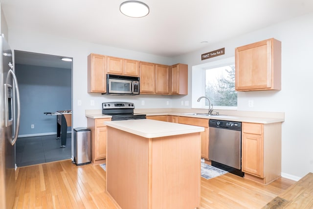 kitchen featuring light brown cabinets, stainless steel appliances, a sink, and light countertops