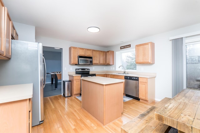 kitchen with stainless steel appliances, light countertops, light wood-style floors, light brown cabinets, and a kitchen island