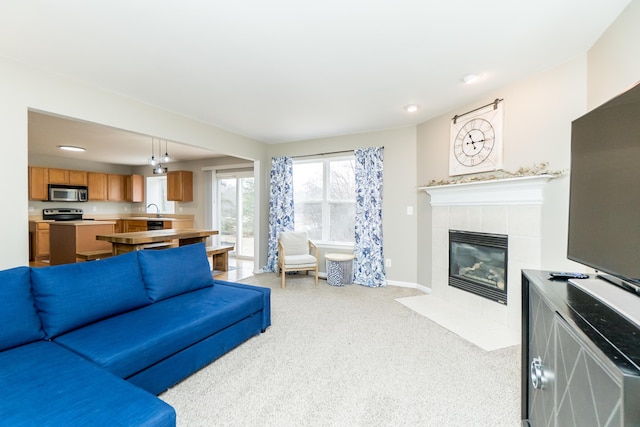 living area featuring light carpet, a fireplace, and baseboards