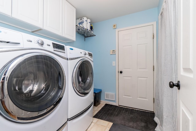 laundry room featuring washer and dryer, visible vents, cabinet space, and dark tile patterned floors