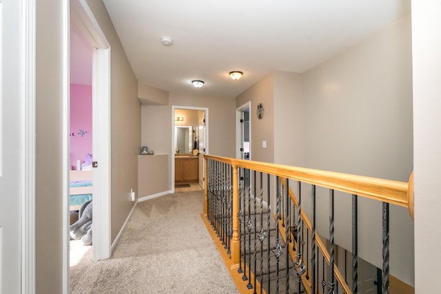 hall with carpet, baseboards, and an upstairs landing