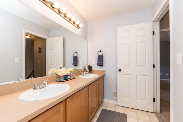 full bath featuring double vanity, a sink, visible vents, and baseboards