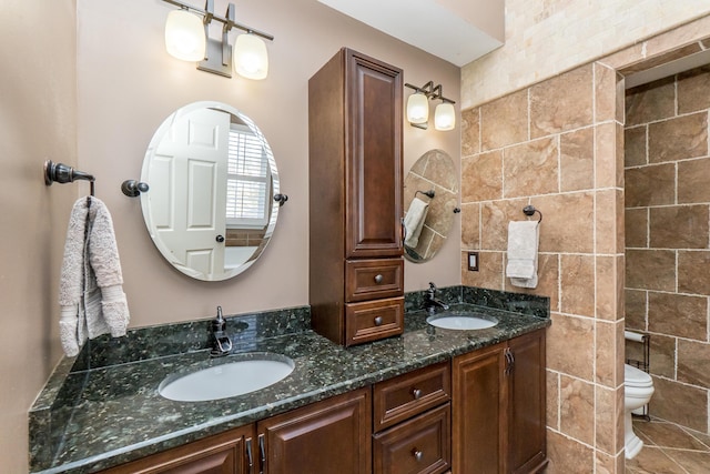 full bathroom with double vanity, a sink, and toilet