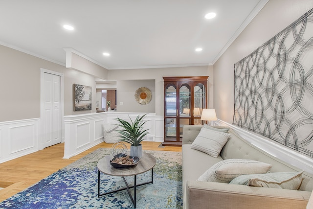 living room featuring a wainscoted wall, light wood-style flooring, ornamental molding, and recessed lighting