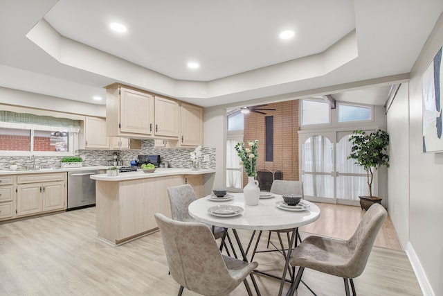 kitchen with light wood-style flooring, light countertops, decorative backsplash, dishwasher, and a wood stove