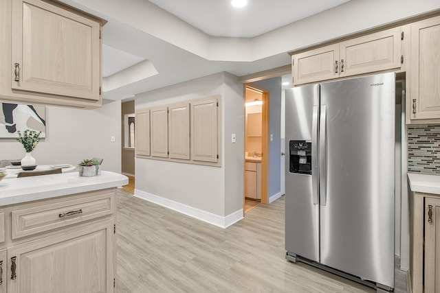 kitchen featuring light wood-type flooring, tasteful backsplash, stainless steel refrigerator with ice dispenser, and light countertops