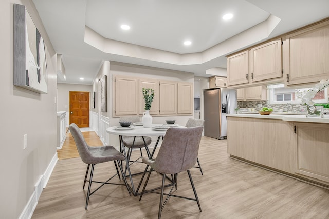 dining area with recessed lighting, a raised ceiling, light wood-style flooring, and baseboards