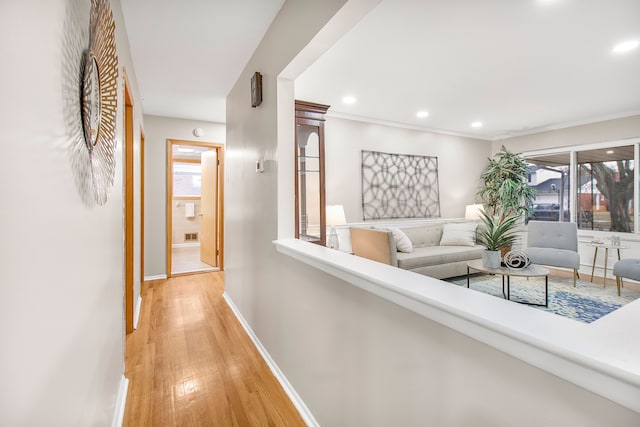 hallway featuring crown molding, recessed lighting, light wood-style flooring, and baseboards