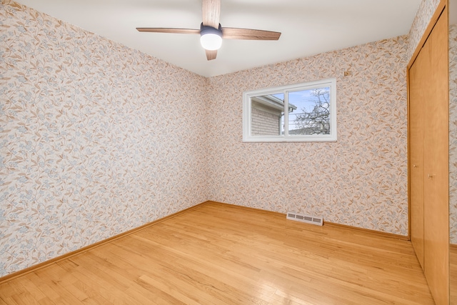 empty room with wallpapered walls, baseboards, visible vents, ceiling fan, and light wood-type flooring