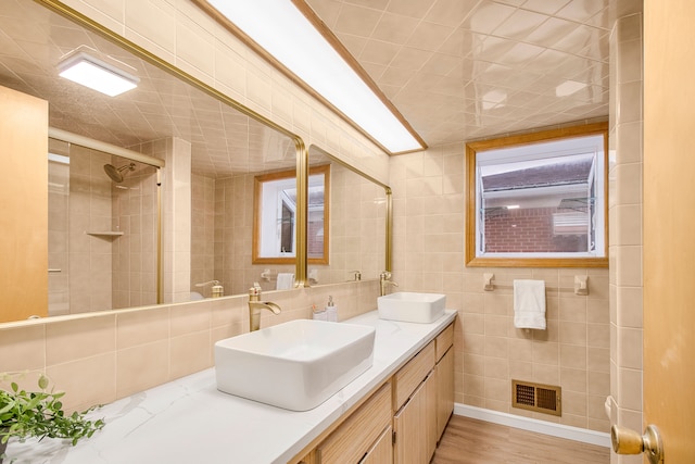 bathroom with visible vents, a sink, and tile walls