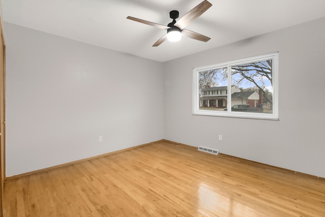 empty room with ceiling fan, light wood-type flooring, visible vents, and baseboards