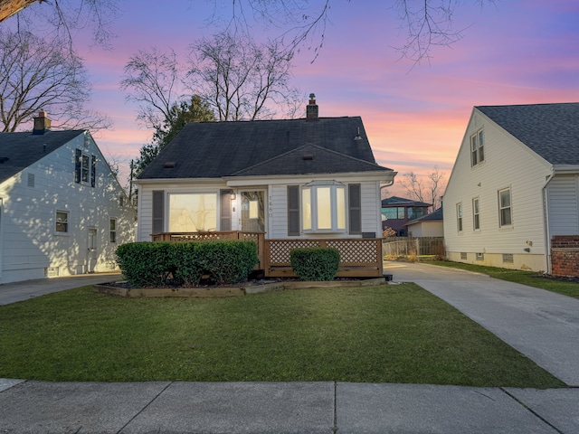 view of front of home featuring driveway, a chimney, a front yard, and fence