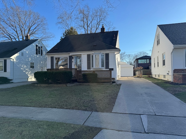 bungalow featuring a front yard, a detached garage, and an outbuilding