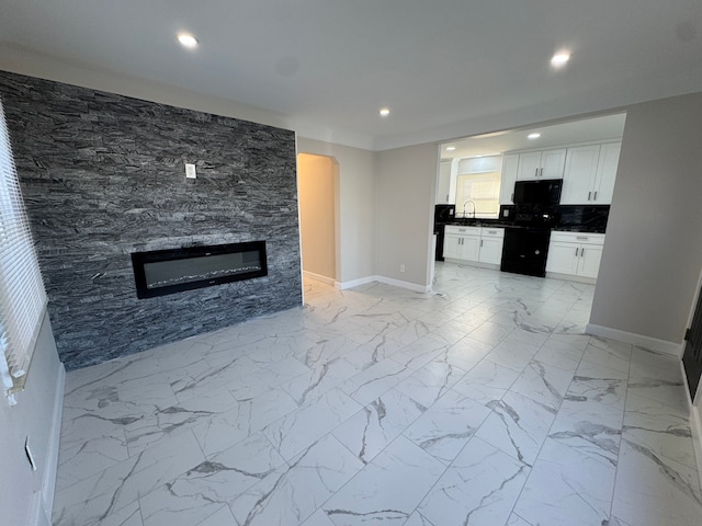 unfurnished living room featuring arched walkways, recessed lighting, a sink, baseboards, and marble finish floor