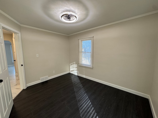 unfurnished room with ornamental molding, dark wood-type flooring, visible vents, and baseboards