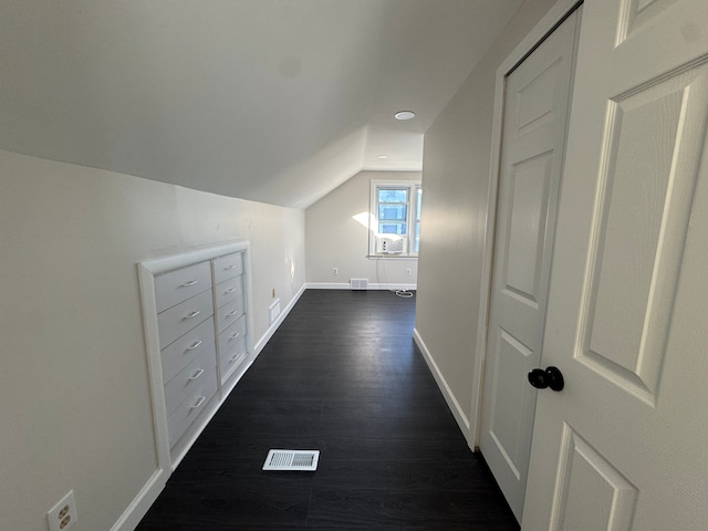 corridor featuring dark wood-style floors, lofted ceiling, visible vents, and baseboards