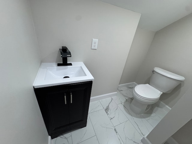 half bath featuring toilet, marble finish floor, baseboards, and vanity